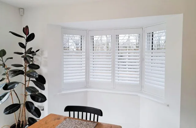Antigua engineered shutters fitted to a white bay window with clean louvre lines.