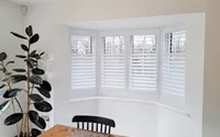 Antigua engineered shutters fitted to a white bay window with clean louvre lines.