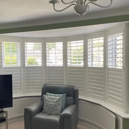 Bay window shutters fitted around a curved interior bay seating area.