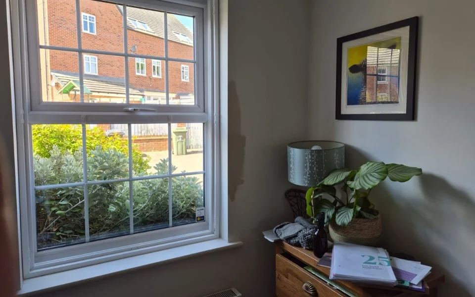 Interior corner in a Bradford home showing a white uPVC window before plantation shutter installation.