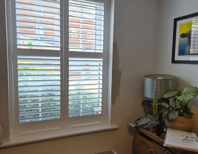 White split-louvre plantation shutters installed on a window in a Bradford property.