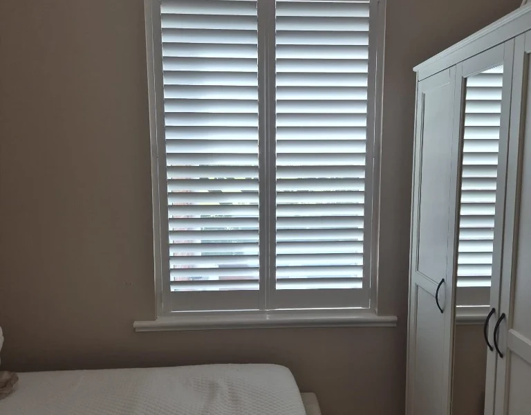 Same Castleford bedroom after white full-height plantation shutters were fitted, louvres open for soft daylight.