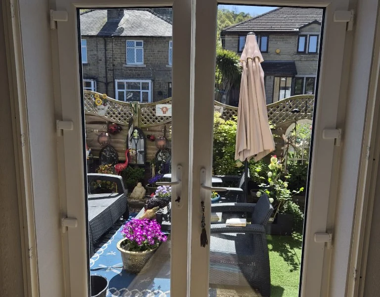 White uPVC French doors opening inwards into a bright room, before plantation shutters were fitted.