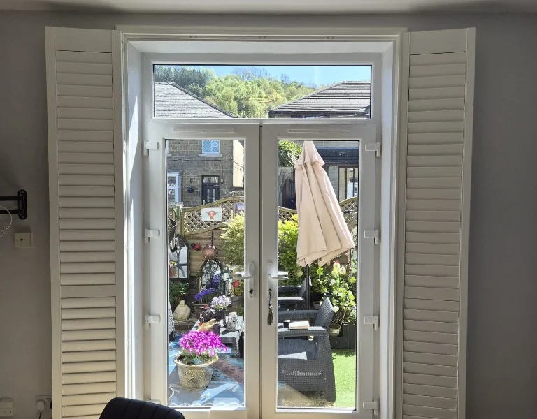 Plantation shutters folded back flat against the walls beside fully visible French doors.