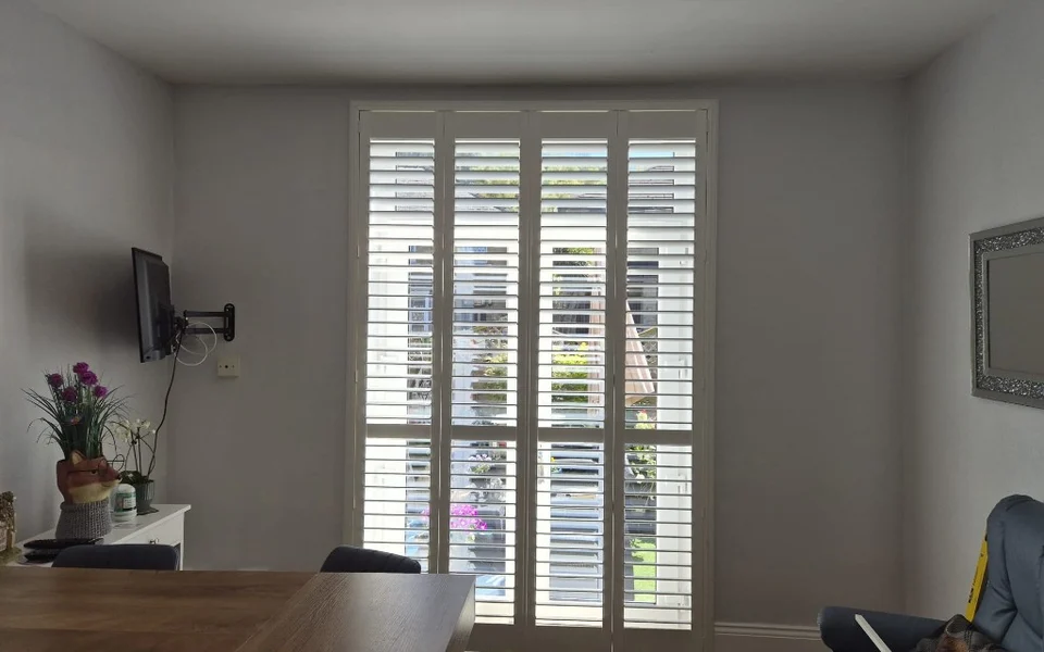 Same French door opening with white plantation shutters featuring a mid-rail for flexible light control.