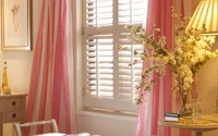 Full-height white plantation shutters in a bright bedroom with independent louvre control.