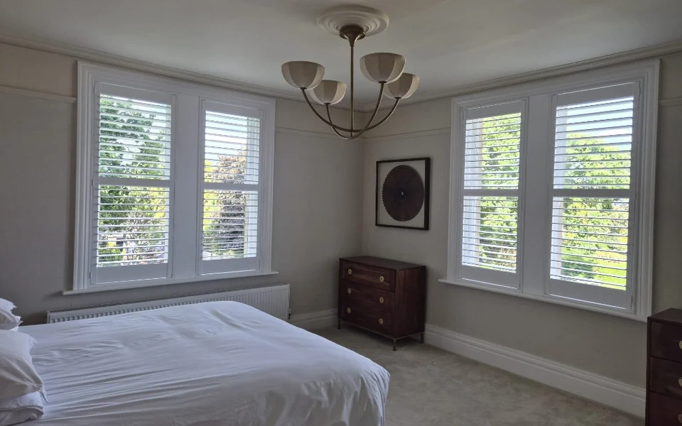 Same Harrogate bedroom after white full-height plantation shutters were fitted on both windows.