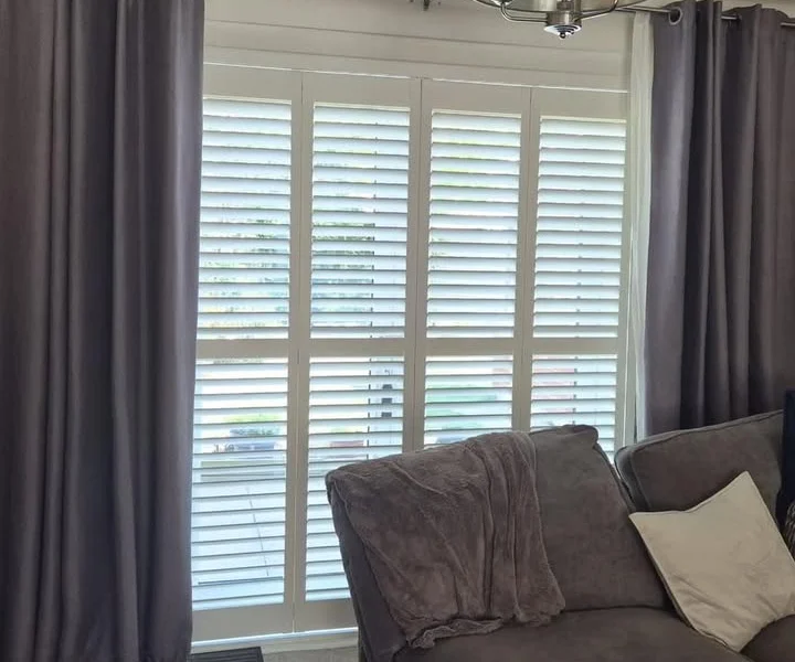 Same Harrogate lounge after four white full-height plantation shutter panels were fitted on the patio doors, louvres open for daylight.