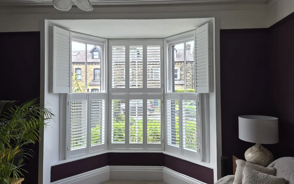 Harrogate bay shutters with upper panels folded open on the side lights and lower panels closed.