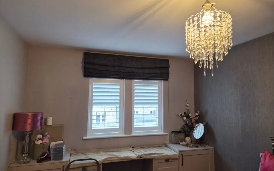 Huddersfield bedroom with mauve-grey walls, dark textured accent wall, and white plantation shutters beside a dressing table.
