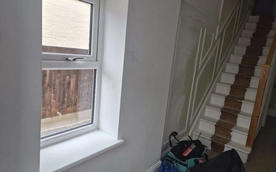 Huddersfield hallway before shutters, a tall recessed window beside the stairs with the stair renovation still in progress.