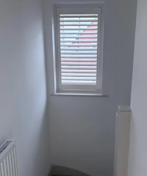 White plantation shutters fitted in a home, shown in a customer Google review photo