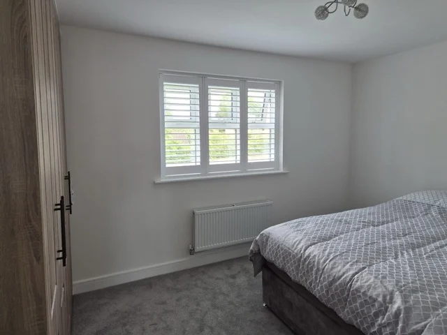 Same Otley bedroom after white full-height plantation shutters were fitted to the three-pane window.