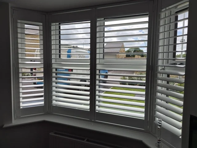 Same Otley lounge bay after white plantation shutters were fitted across all four panels.