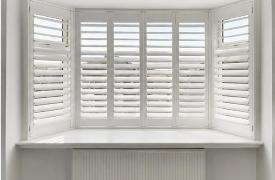 Same Pontefract display bay after white plantation shutters were fitted across all three sections, louvres open with daylight on the sill.
