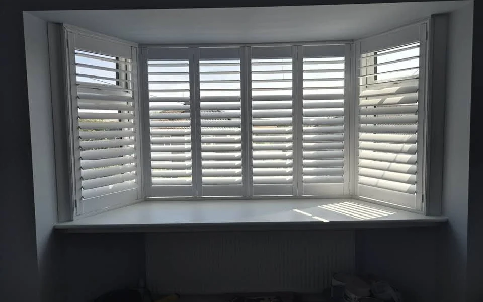 Same Pontefract display bay after white plantation shutters were fitted across all three sections, louvres open with daylight on the sill.