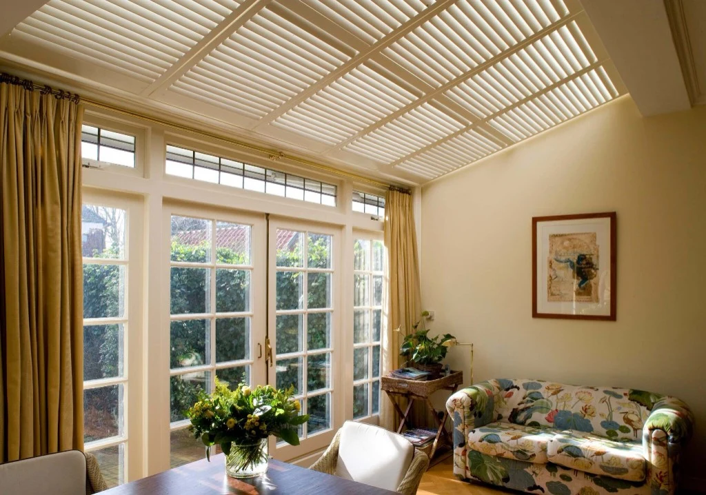 Skylight shutters installed across a bright glazed ceiling room.