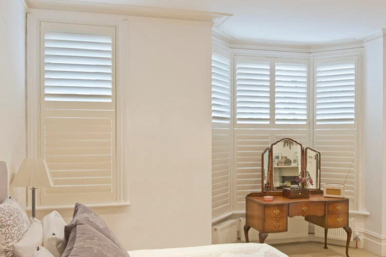White plantation shutters fitted to a curved bay window, showing clean lines and even louvres.