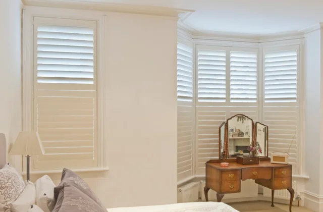 White plantation shutters fitted to a curved bay window, showing clean lines and even louvres.