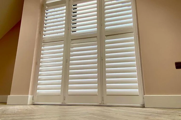 Special shaped shutters fitted to a tall gable window with angled top sections.