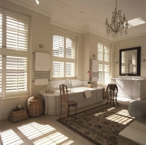 Tier-on-tier shutters in a spacious bathroom with multiple windows.