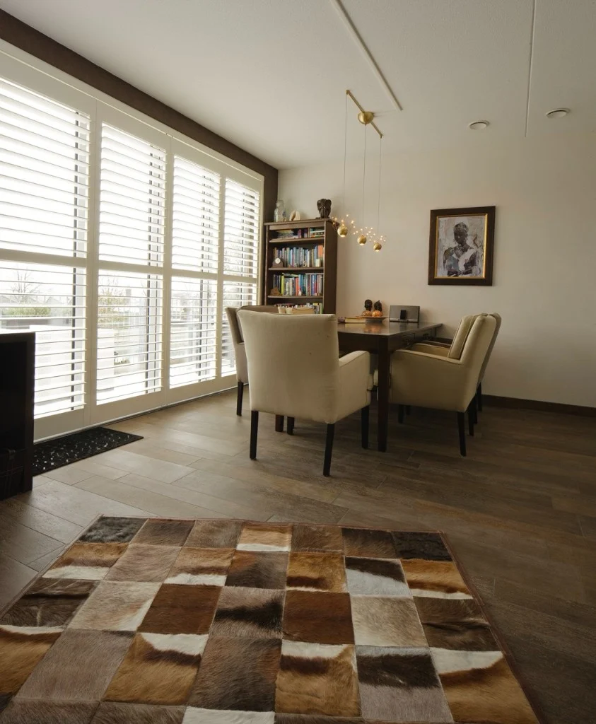 Large glazed opening with track shutters in a modern dining room.