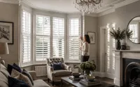 Woman adjusting white plantation shutters on a bay window in a Harrogate living room