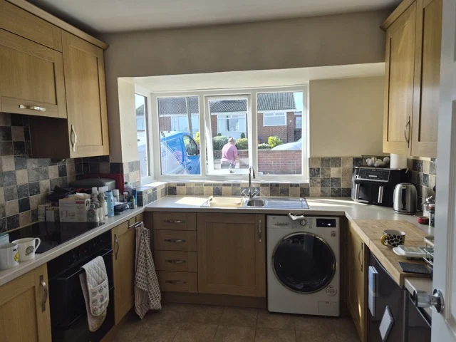 Wakefield kitchen window above the sink before shutters, with oak cabinets and a tiled backsplash.