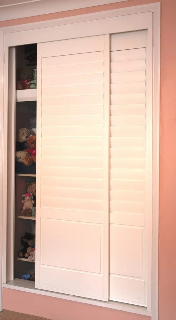 Sliding wardrobe shutter doors in a pink bedroom.
