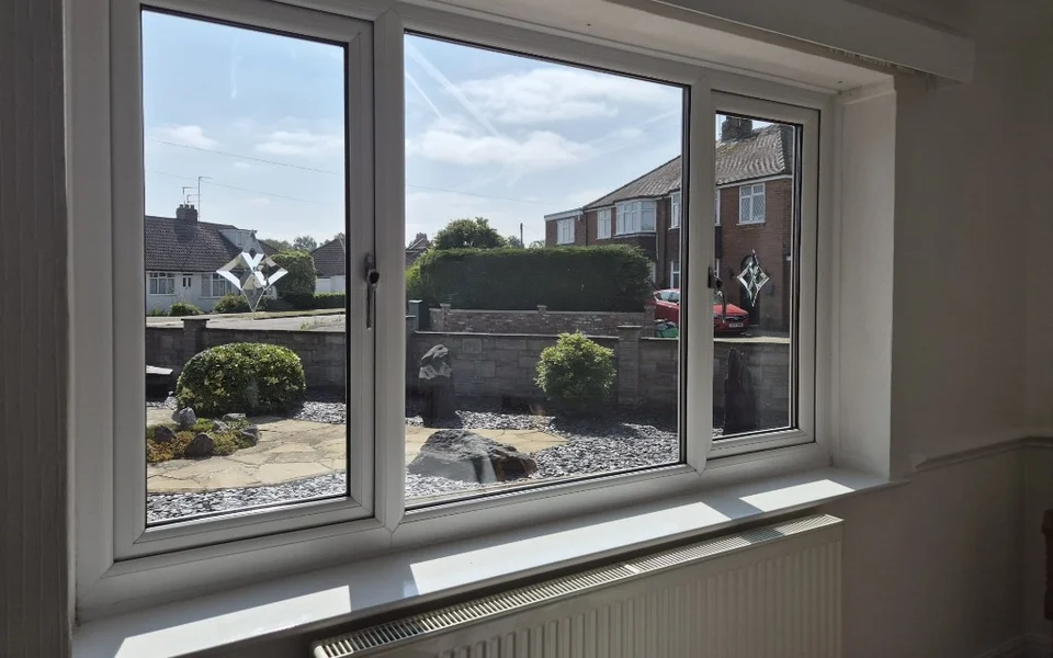 York kitchen-diner window before shutters, three-section white uPVC window with decorative leaded side lights and a radiator below.