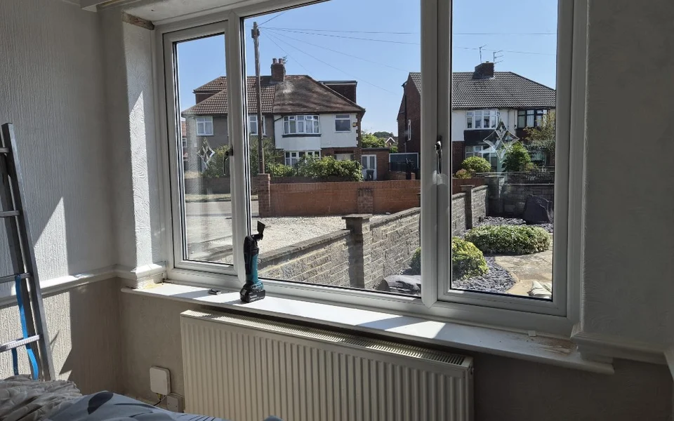 York lounge window before shutters, three-section white uPVC window with leaded side lights, radiator below, and tools on the sill.